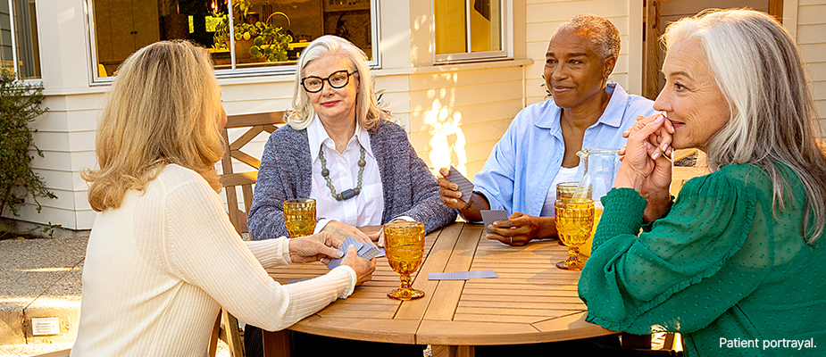 A group of women sitting around a table playing cards outdoors.