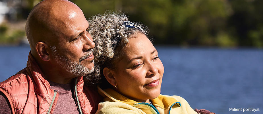A man and woman sitting together near a lake.