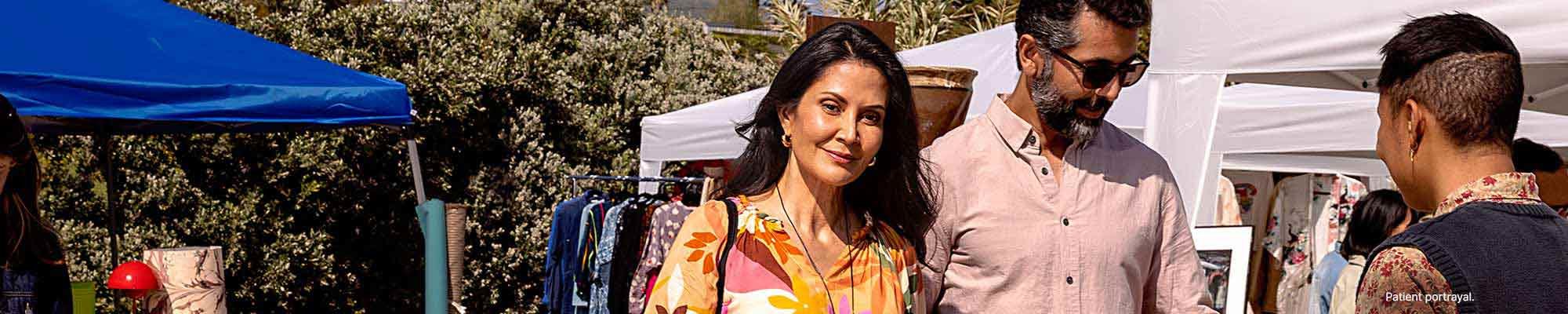 A man and woman shopping at a flea market on a sunny day.