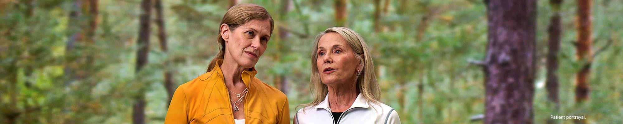 Two women having a conversation in a wooded area.