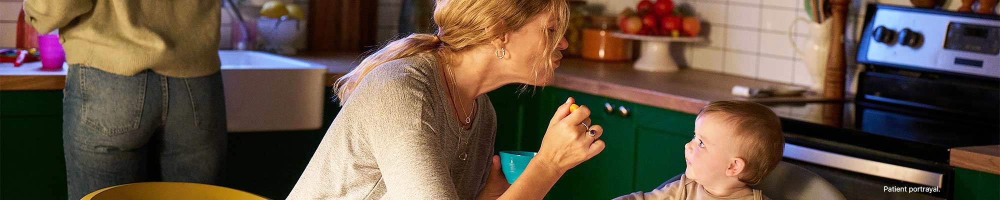A woman feeding a baby in the kitchen.