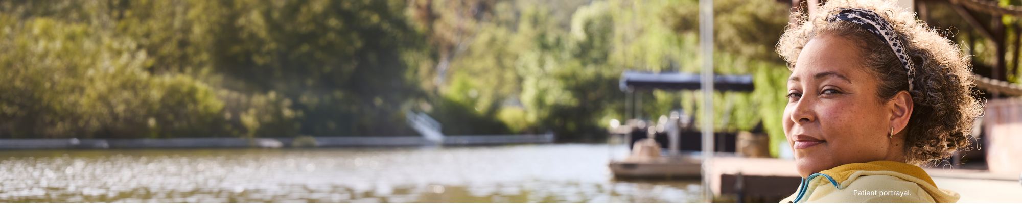 Person sitting beside a lake with trees in the background